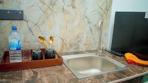 A kitchen with a marble backsplash, a stainless steel sink, and a tray with water bottles and glasses. - Villa Roberocia  (Hikkaduwa)