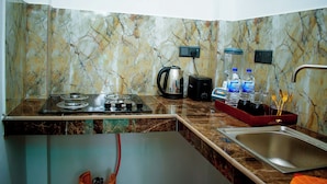 A kitchen with a gas stove, a kettle, a sink, and a marble backsplash. - Villa Roberocia  (Hikkaduwa)