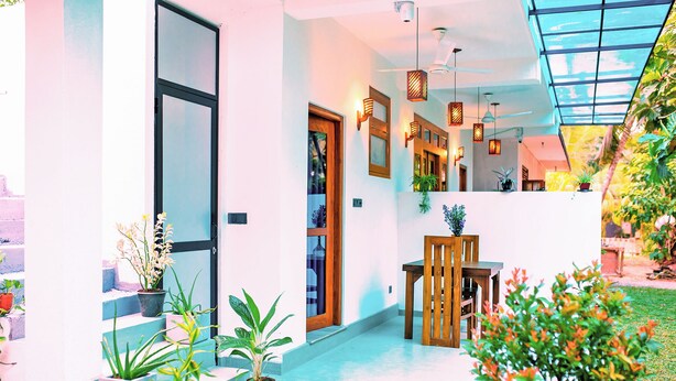 A modern building with a glass ceiling, potted plants, and a wooden table. - Villa Roberocia  (Hikkaduwa)