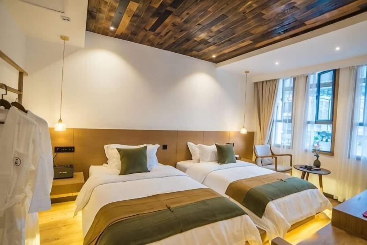 A hotel room with two beds, wooden ceiling, and a view of the city.
