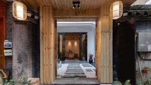 A wooden entrance with a stone pathway leading to a room with a table and chairs. - Feng Mian Su She Guesthouse (Fenghuang)