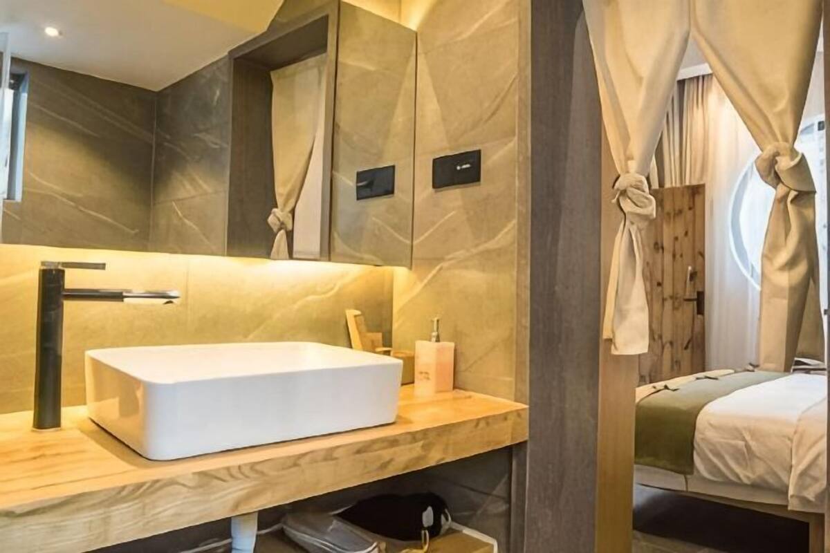 A modern bathroom with a large mirror, a rectangular sink, and a wooden vanity.