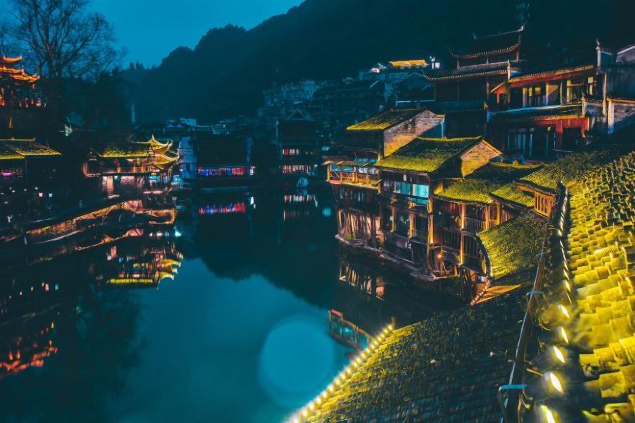 Ein traditionelles chinesisches Dorf mit Wasserstraßenreflexionen, traditioneller Architektur und beleuchteten Gebäuden.