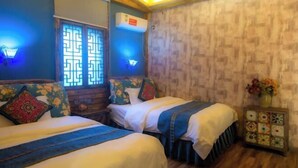 A room with two beds, a window with decorative lattice, an air conditioning unit, and a small table with a vase of flowers. - Hotel Baihui Inn (Zhangjiajie Pedestrian Street Dayong Ancient City Inn）) (Zhangjiajie)
