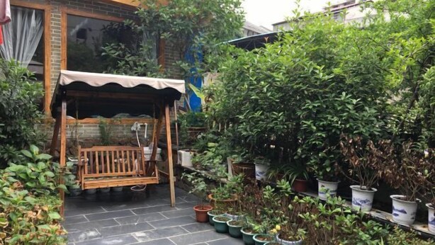 A small patio area with a wooden bench under a canopy, surrounded by potted plants and a brick wall. - Hotel Baihui Inn (Zhangjiajie Pedestrian Street Dayong Ancient City Inn）) (Zhangjiajie)