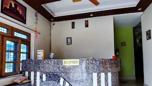 A reception area with a marble counter, ceiling fan, and framed pictures on the walls. - Nature villa Kyarki (Rishikesh)