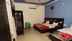 A bedroom with a bed, a green chair, a ceiling fan, and a decorative ceiling design. - Nature villa Kyarki (Rishikesh)
