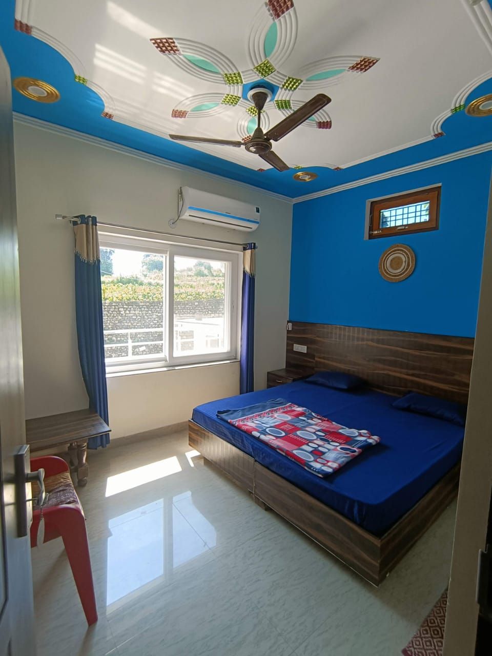 Un dormitorio con cama, aire acondicionado, ventana con cortinas y ventilador de techo.