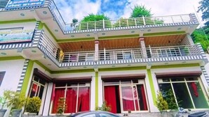 A two-story building with a balcony on the upper floor, a car parked in front, and a scooter to the right. - Nature villa Kyarki (Rishikesh)