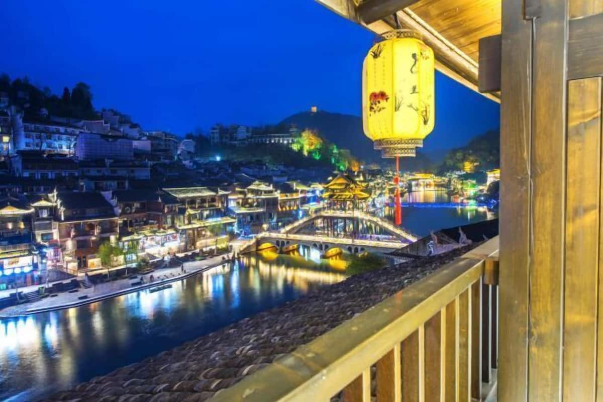 A traditional Chinese town with illuminated buildings, a bridge, and a river.