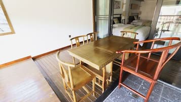 Una habitación con una mesa y sillas de madera, una cama con colcha blanca y una ventana con vistas.