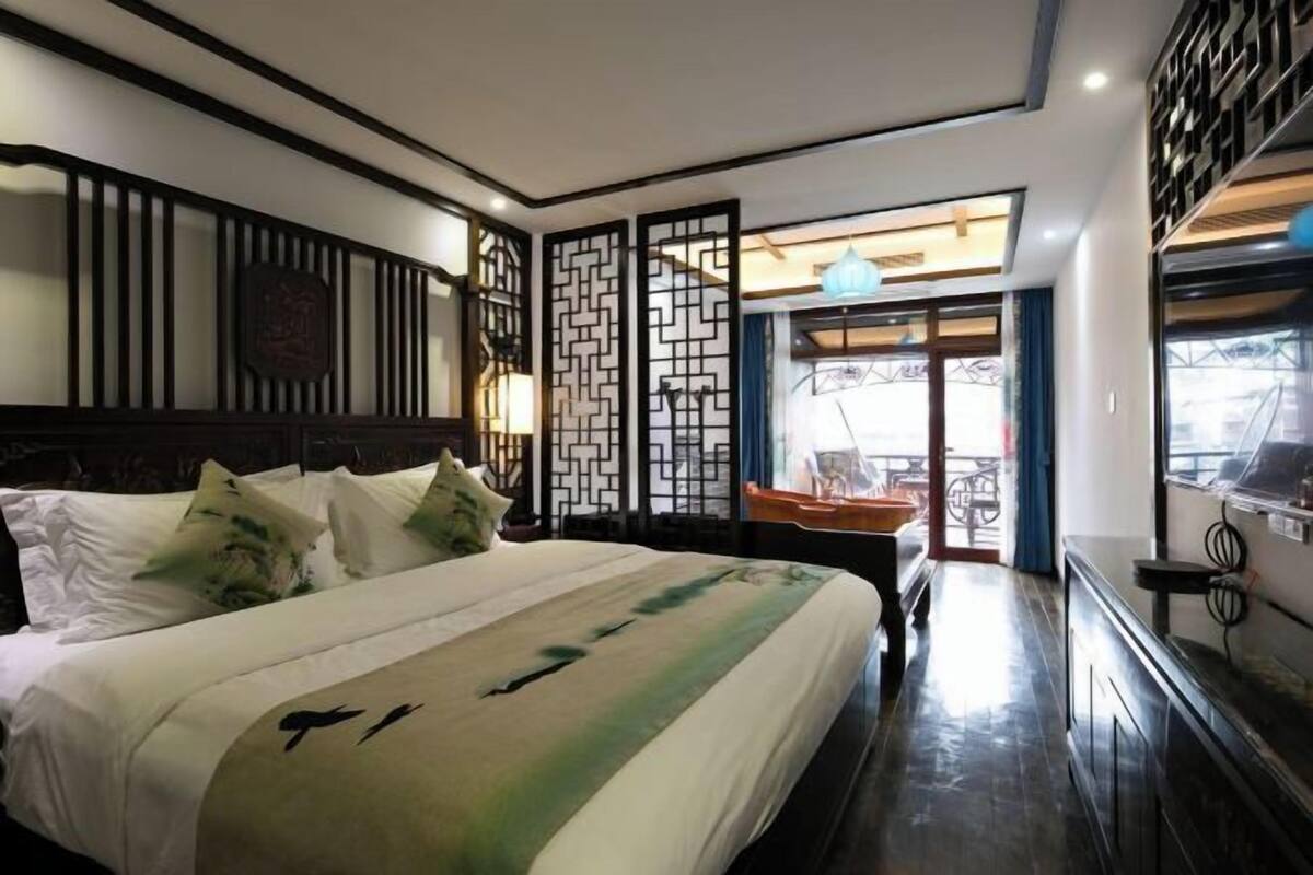 A hotel room with a bed, a desk, a chair, a window, and a view of the outside.