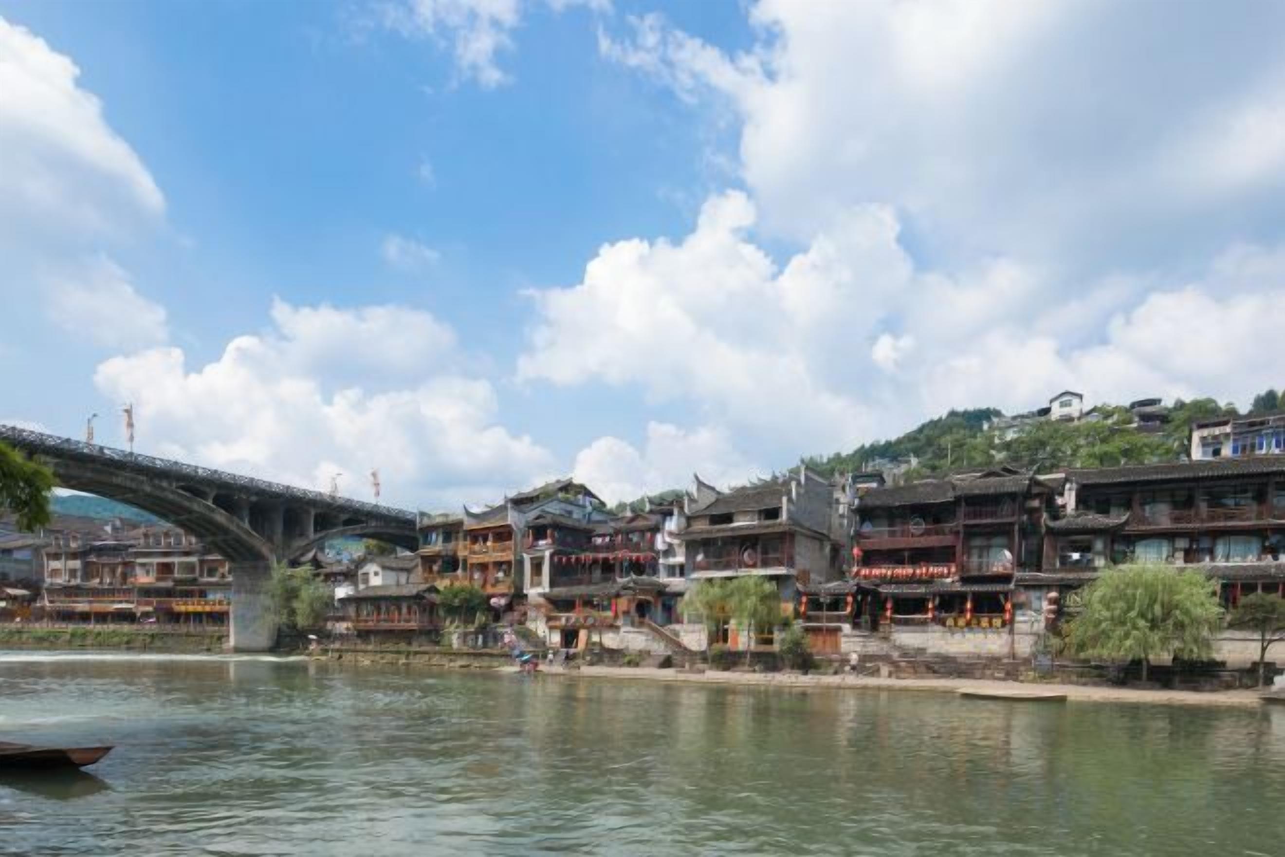 Un pueblo a orillas del río con arquitectura tradicional, un puente y una masa de agua tranquila.