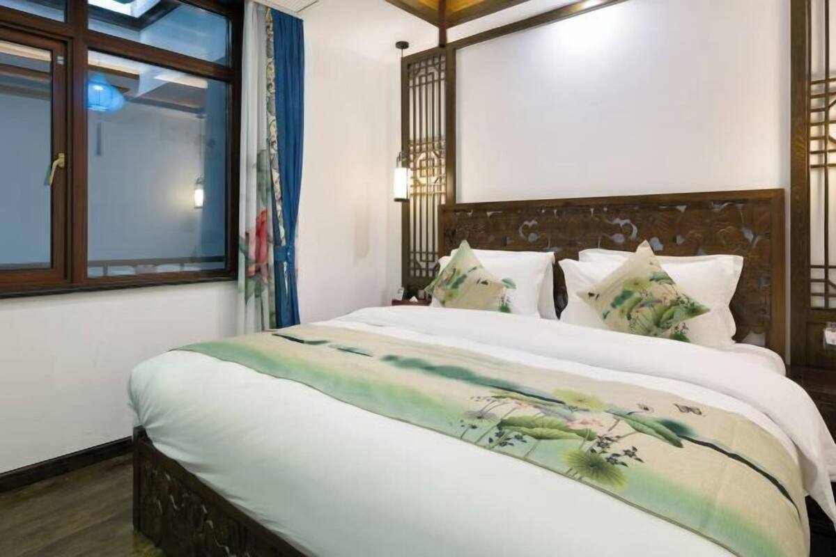 A bedroom with a bed, curtains, a window, and a decorative wall panel.
