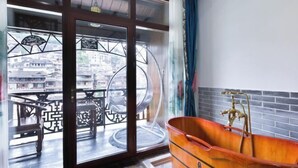 Ein Zimmer mit einem großen Fenster, einer Holzbadewanne und einem Balkon mit Tisch und Stühlen.