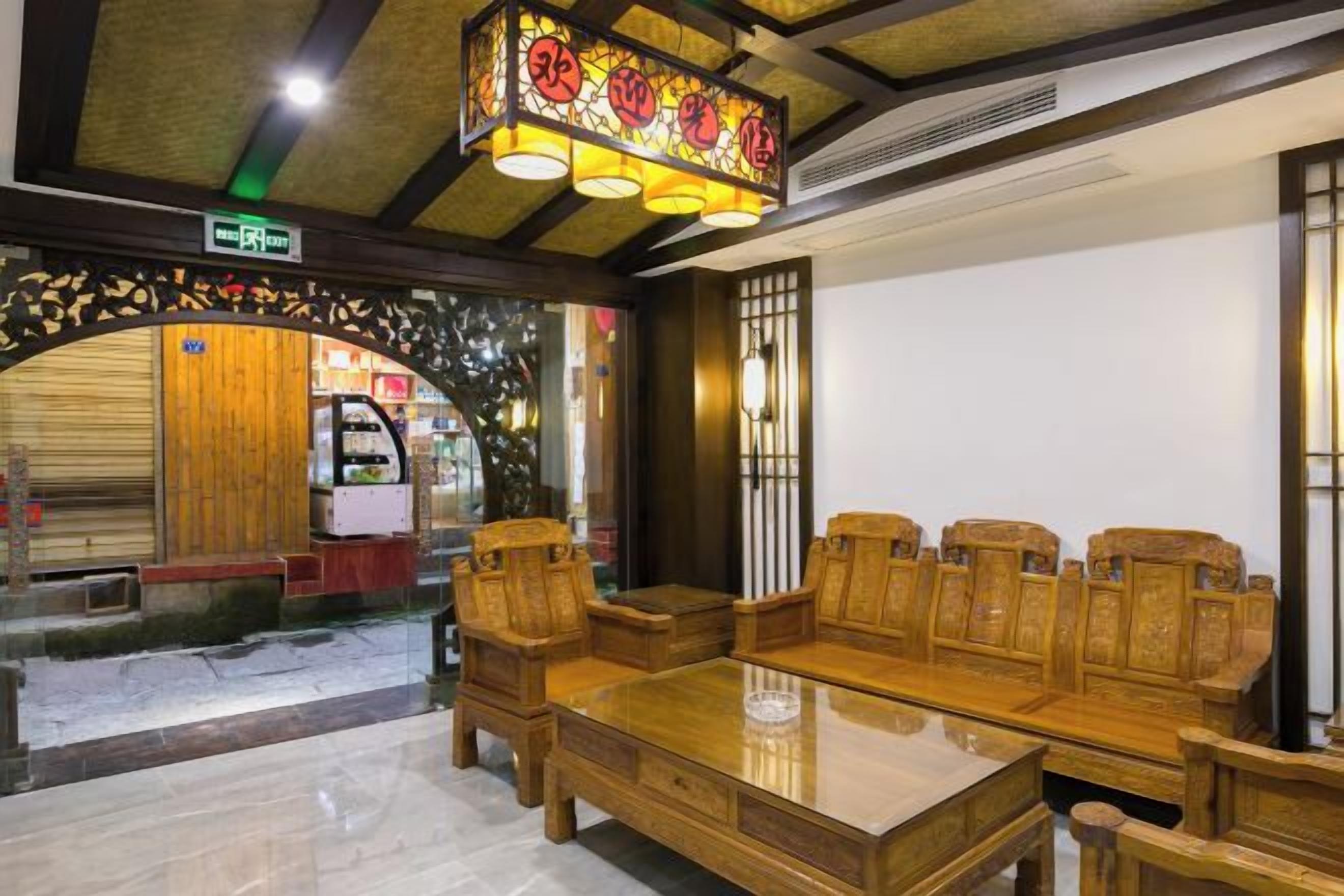Un comedor tradicional de madera con una mesa larga y sillas, una lámpara decorativa en el techo y vista a la calle.