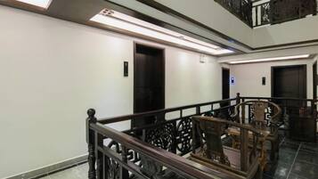 Ein Hotelinnenraum mit Treppe, Holzgeländern und einem modernen Aufzug.