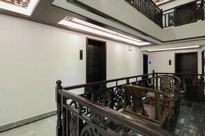 A hotel interior with a staircase, wooden railings, and a modern elevator. - Floral Hotel ·Fenghuang Grand Riverview (Fenghuang)