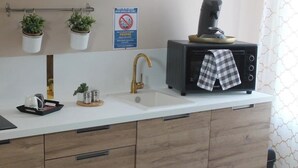 A kitchen with a white countertop, wooden cabinets, a coffee maker, a kettle, and a sign prohibiting smoking. - Romantic Escape & Jacuzzi! Near Zoo Beauval (PRUNIER EN SOLOGNE)