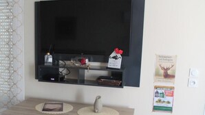 Un comedor con un televisor sobre la mesa, dos sillas y un estante con objetos.