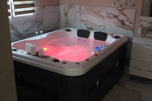 Un bain à remous agrémenté de pétales de rose, de bougies et d’un panneau de commande.