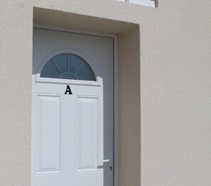 A white door with a window above it and the letter 'A' on the door.
