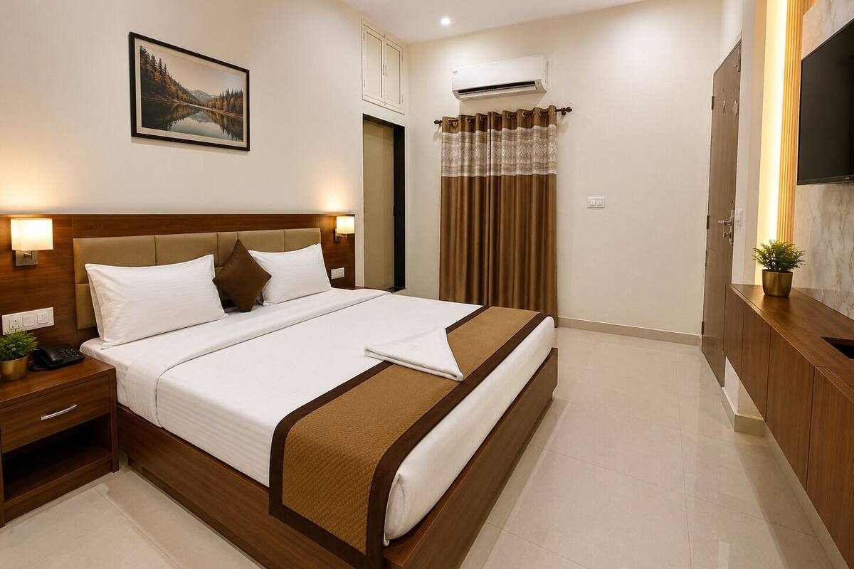 Habitación de hotel con cama, mesita de noche, lámpara, equipo de aire acondicionado y un cuadro en la pared.