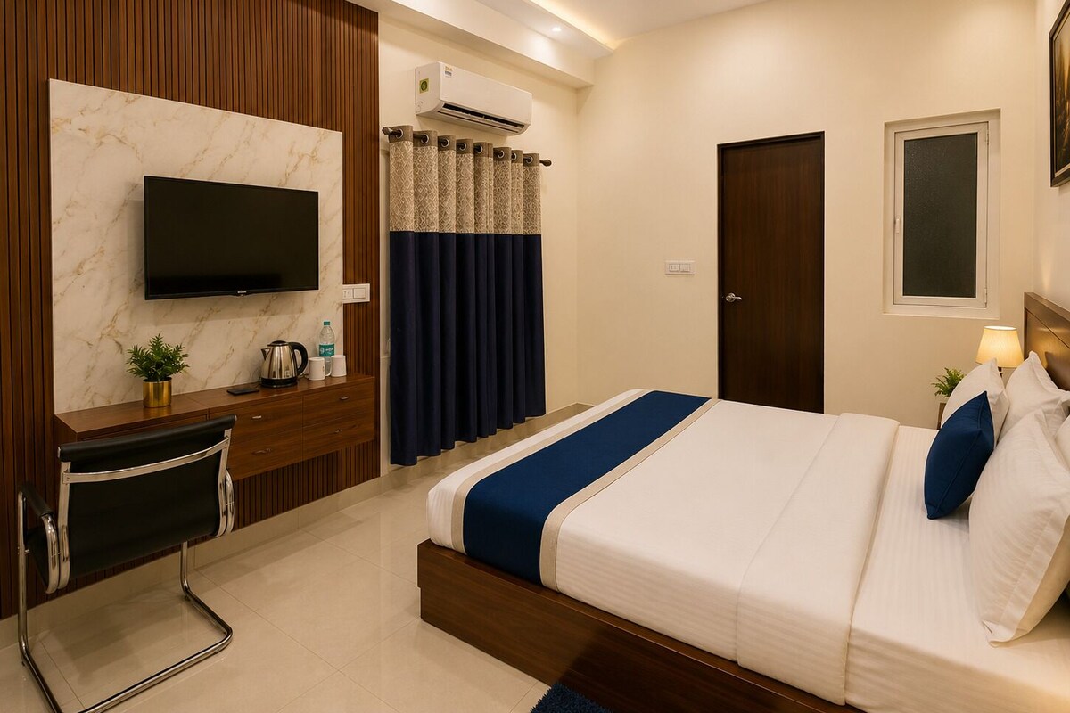 A hotel room with a bed, a desk with a chair, a television, an air conditioning unit, and a window.