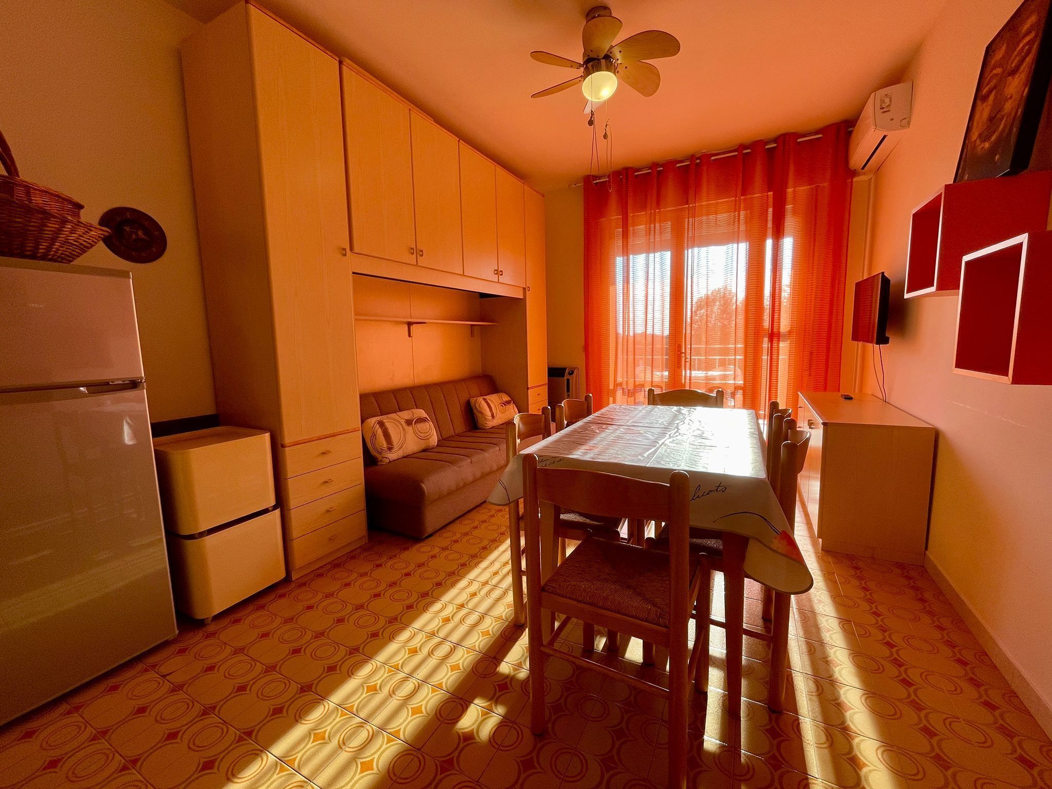 Uma cozinha compacta com mesa de jantar, sofá e ventilador de teto.