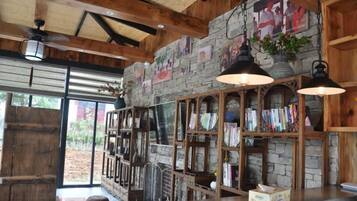 A rustic interior with exposed wooden beams, stone walls, and a bookshelf.