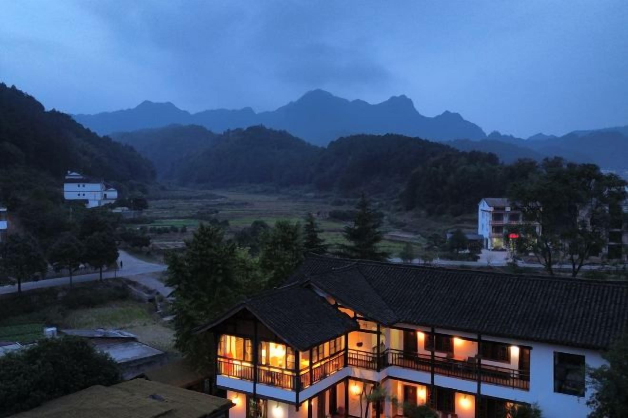 A two-story building with a balcony, surrounded by a mountainous landscape.