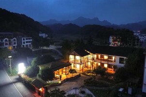 Un edificio de dos pisos con una entrada bien iluminada y un camino de acceso a la entrada principal.