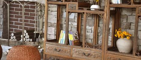 Un mueble de madera con varios estantes y cajones, una cesta tejida y un florero con flores.