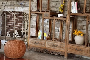 Un mueble de madera con varios estantes y cajones, una cesta tejida y un florero con flores.