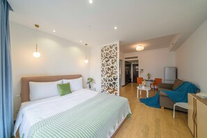 Una habitación de hotel moderna con una cama grande, un televisor, un sofá y un área de comedor.