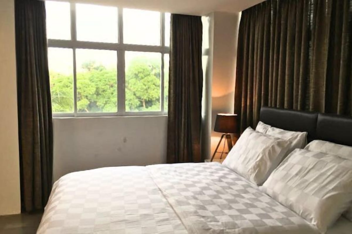 Habitación de hotel con una cama grande, una ventana con cortinas y vistas a zonas verdes.