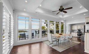 A spacious dining area with a view of a lake, large windows, and a ceiling fan. - Rivercliff Ridgehouse @ Beaver Lake (Rogers)