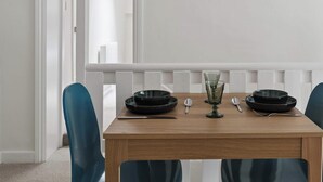 A dining table with two black plates, a glass, and silverware, set against a white wall with a door in the background. - Old Bell Annexe - Cosy 1Bed Stay in Central Henley (Henley-on-Thames)