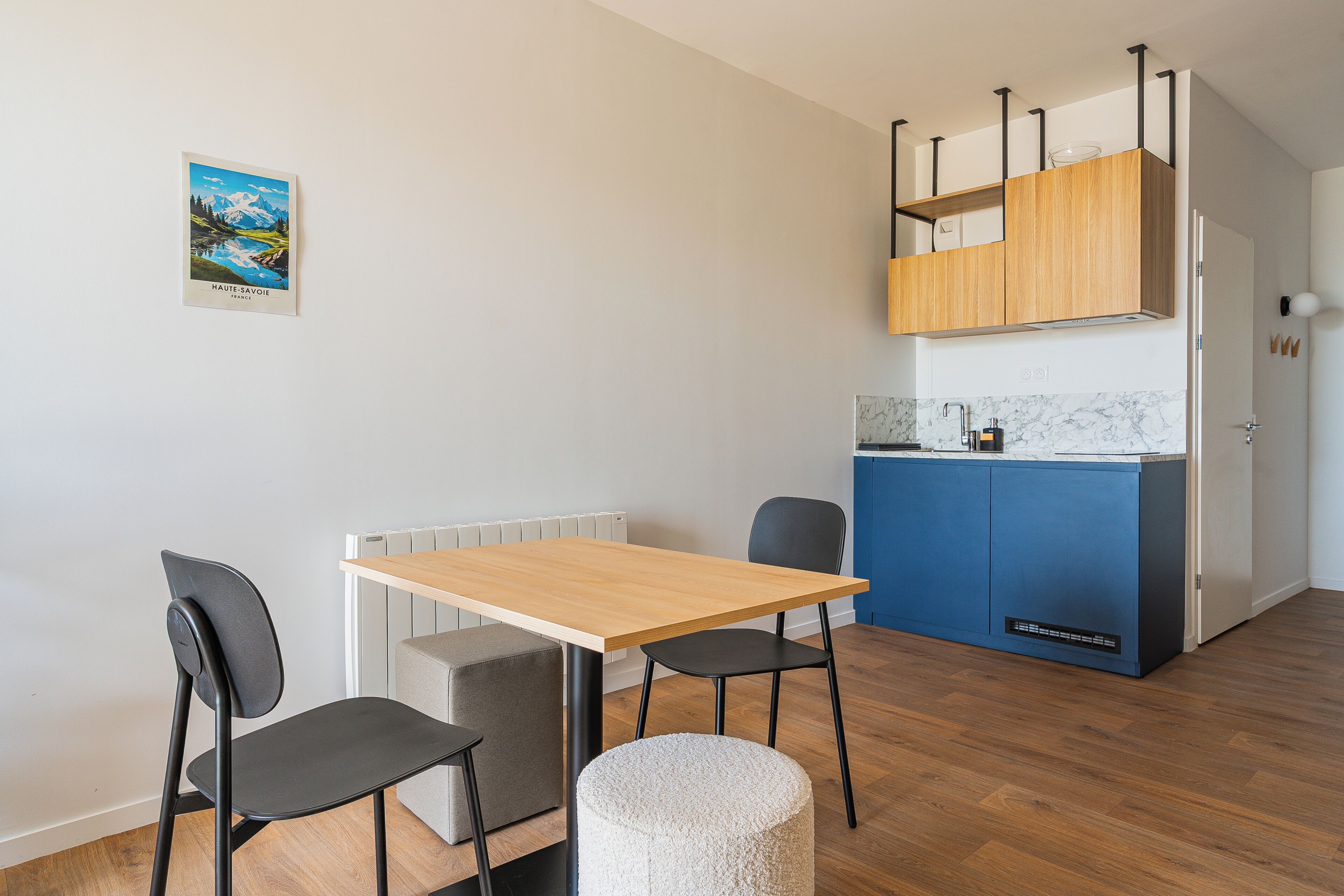 A compact kitchen with a wooden countertop, a blue appliance, and a white radiator.