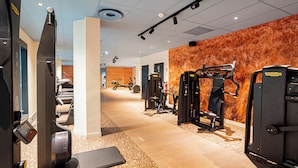 A gym with exercise equipment, a treadmill, and a wall with a textured pattern. - Ecla Genève Archamps (Archamps)