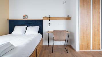 Ein Schlafzimmer mit einem Bett, einem Schreibtisch, einem Stuhl und einem Holzschrank.