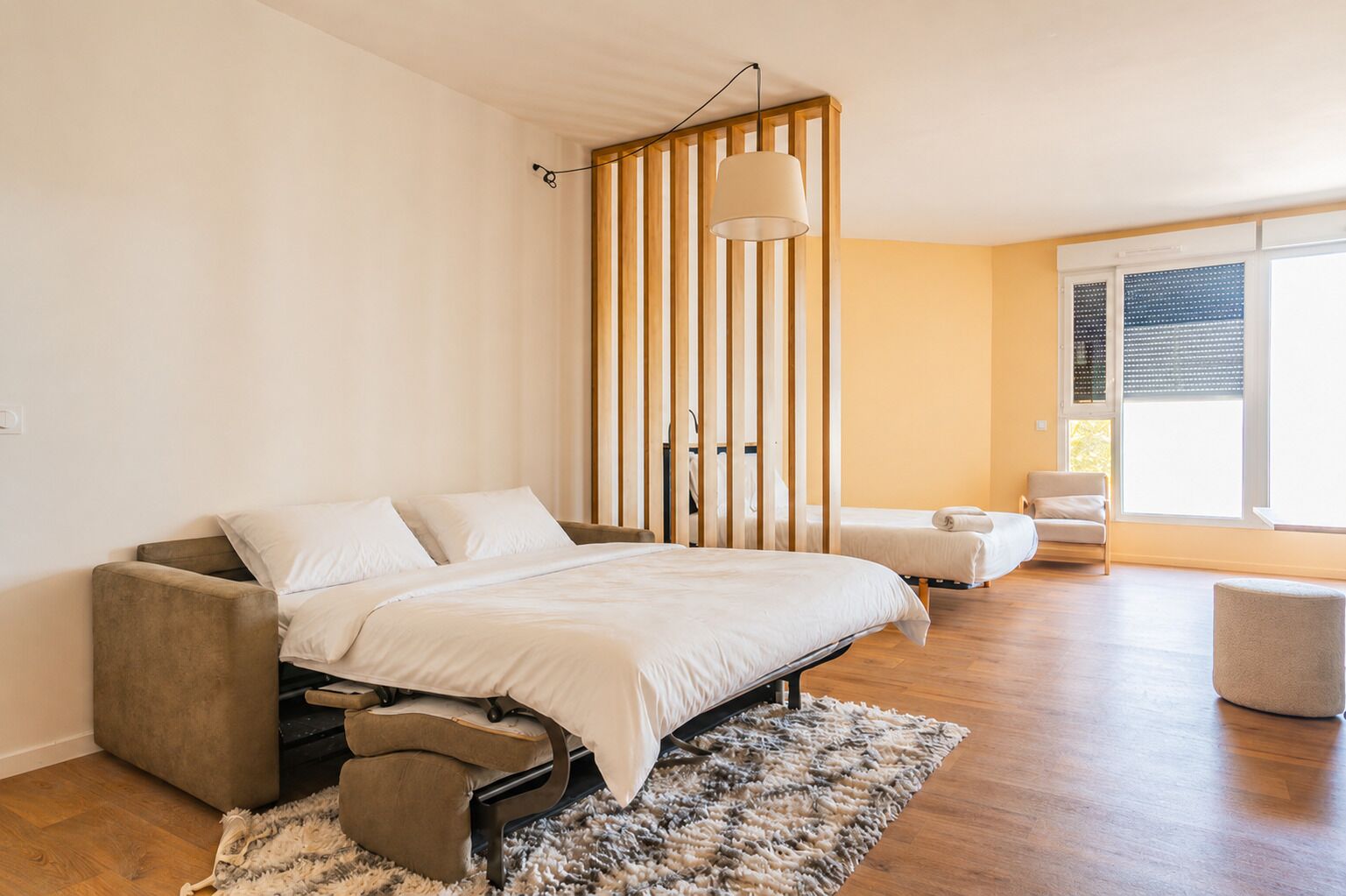 Une chambre à coucher comprenant un lit, une chaise, un canapé, une fenêtre et une vue sur l’extérieur.