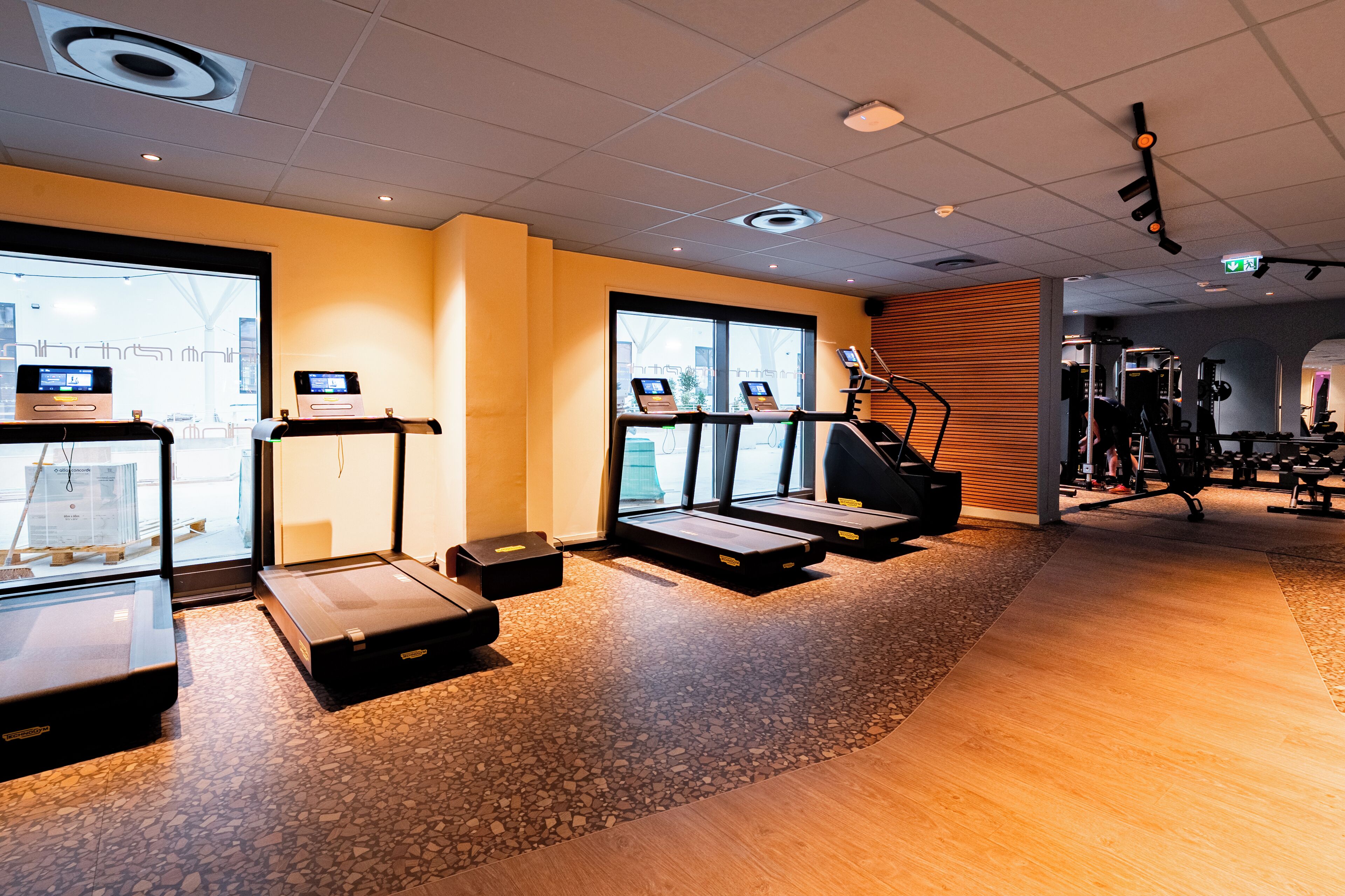 Ein Fitnessraum mit Laufbändern, Fahrrädern und Kraftgeräten.