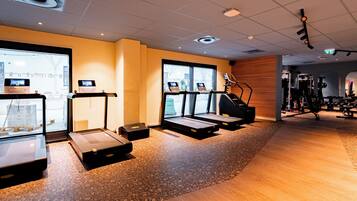 Ein Fitnessraum mit Laufbändern, Fahrrädern und Kraftgeräten.