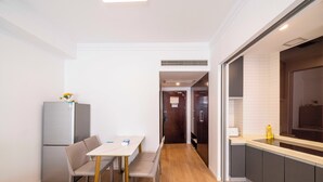 A compact kitchen with a dining area, a refrigerator, and a sink. - Tyms Xuhui Spacious 1BR APT  (Shanghai)