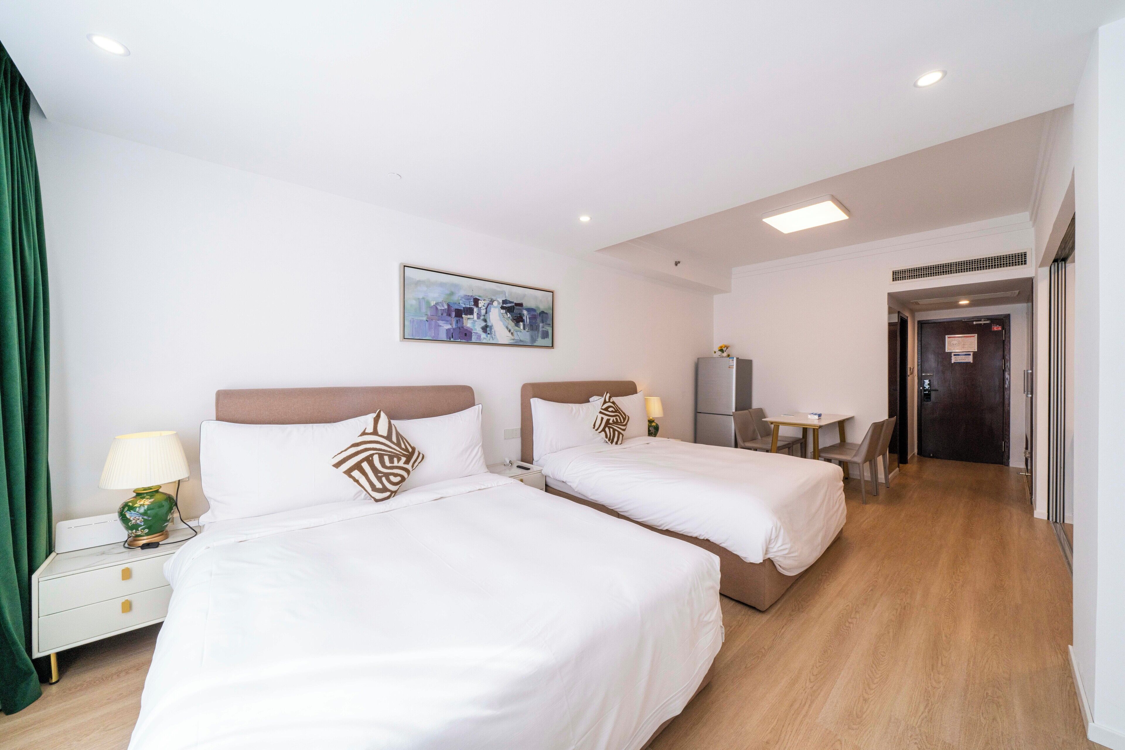 A hotel room with two beds, a desk, and a chair.