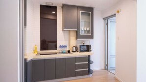 A modern kitchen with grey cabinets, a microwave, and a glass-fronted cabinet. - Tyms Xuhui Spacious 1BR APT  (Shanghai)