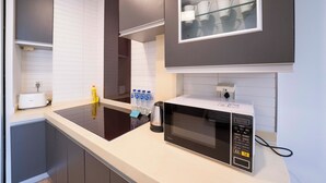 A modern kitchen with a microwave, toaster, and water bottles on the counter. - Tyms Xuhui Spacious 1BR APT  (Shanghai)