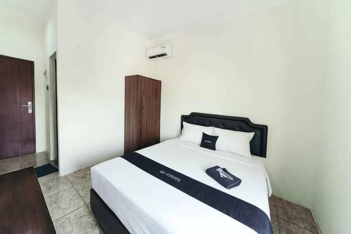 A hotel room with a bed, a wardrobe, and a door.