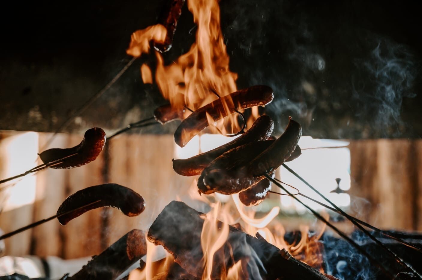 Sausages being grilled over an open flame.